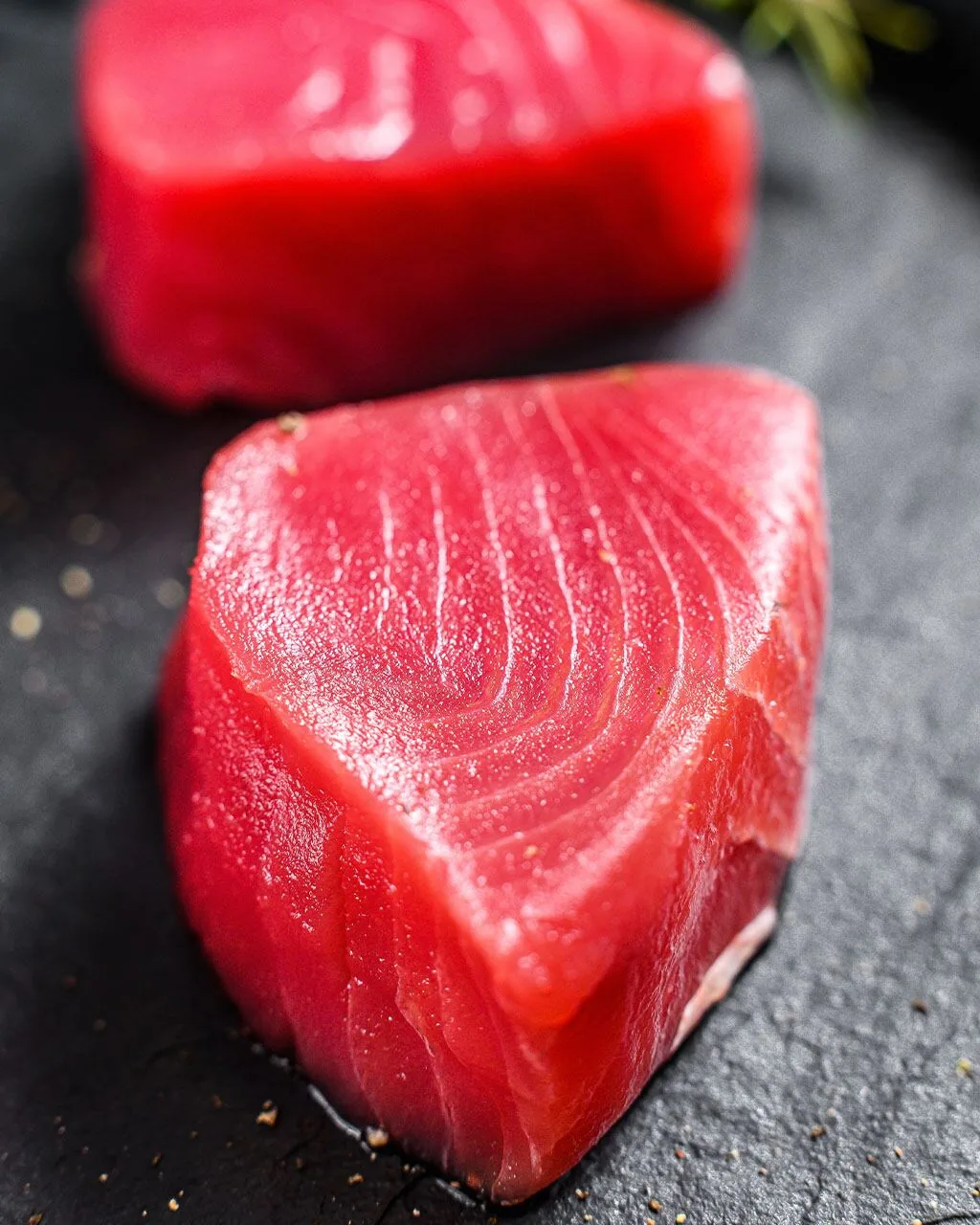 Whole tuna and sliced loins on dark slate